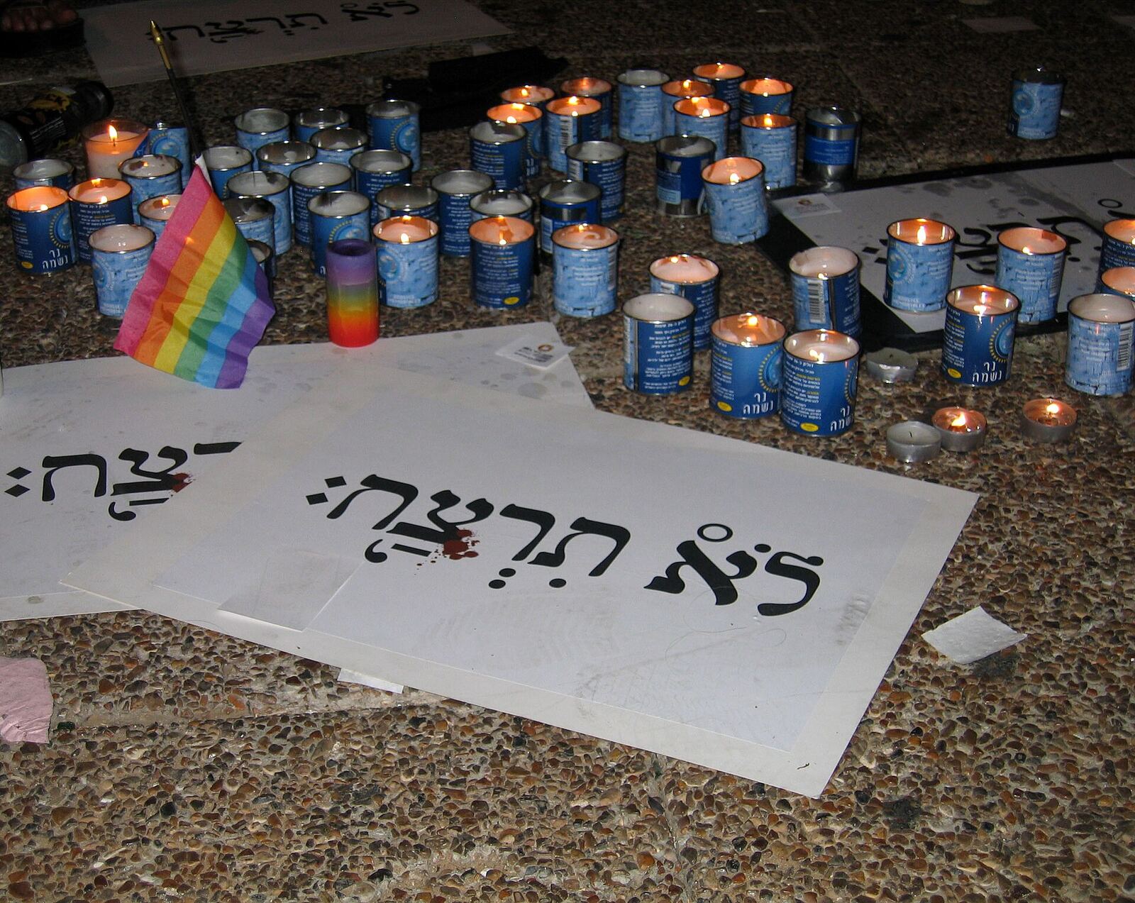 Yahrzeit candles and signs entitled " לא תרצח " ( Thou shalt not murder ) at a solidarity rally at Rabin Square for the victims of the 2009 Tel Aviv gay centre shooting .